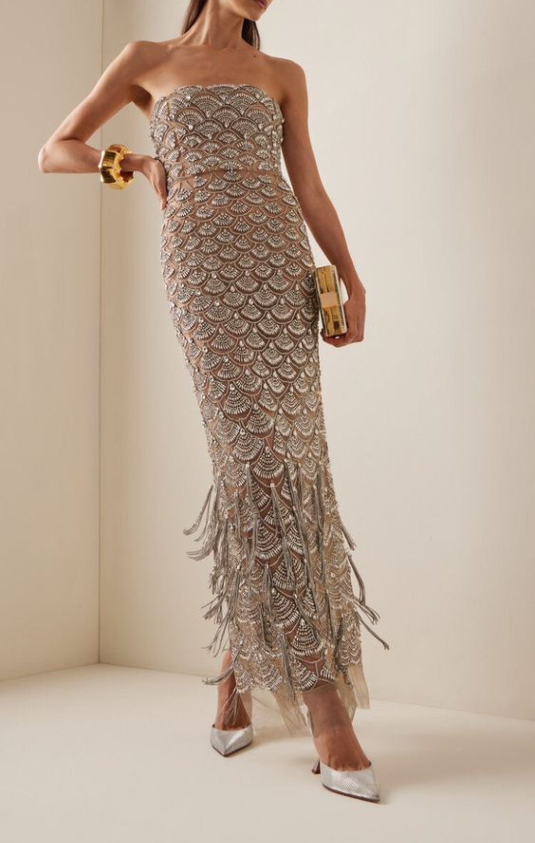 Woman in silver long dress with shaggy detailing on lower half and white high heels.