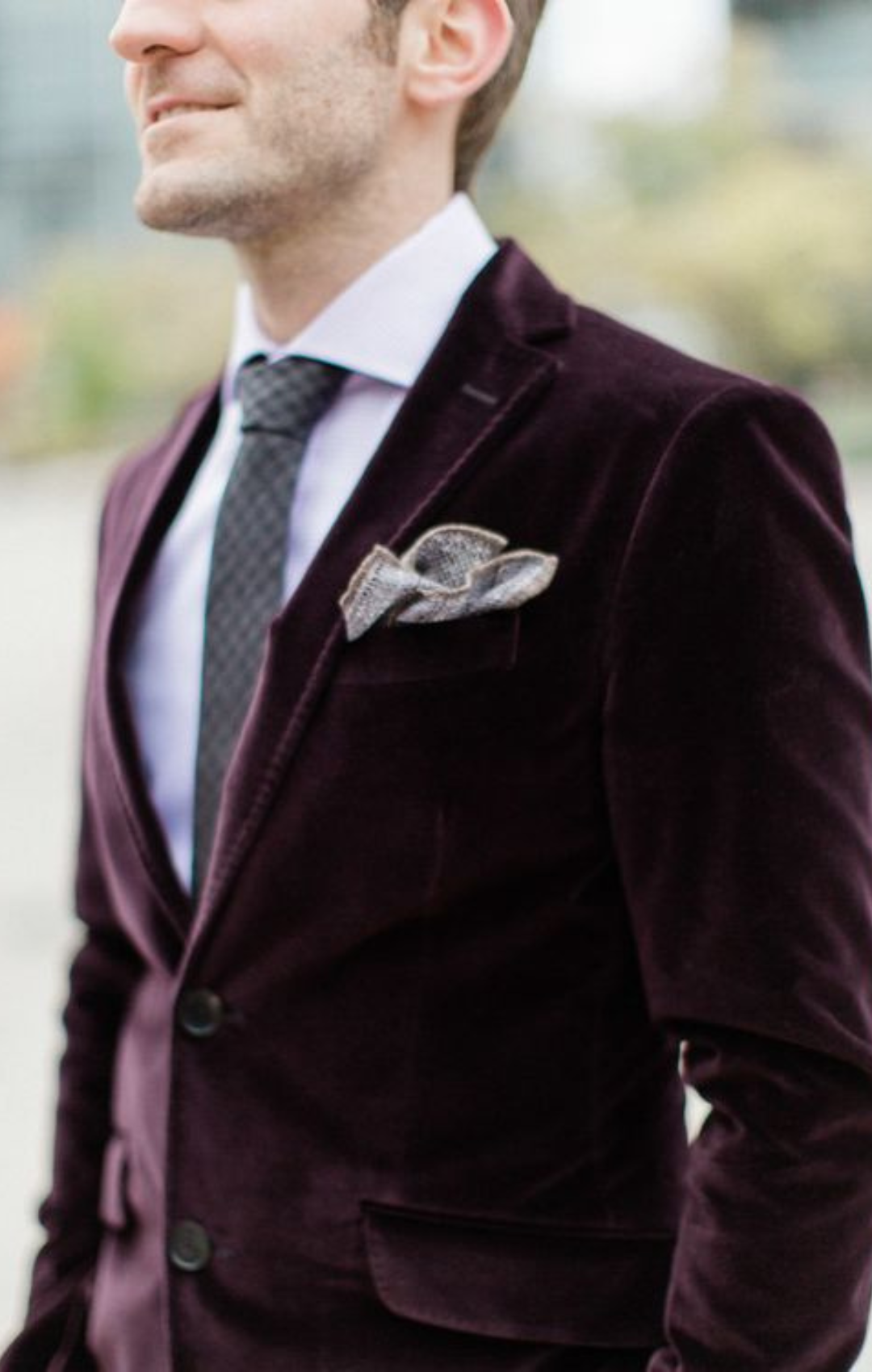 Man in burgundy velvet suit jacket with gray pocket square.