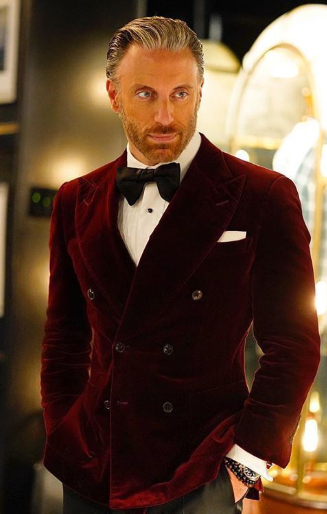 Man in dark red suit jacket with white shirt and bow tie.